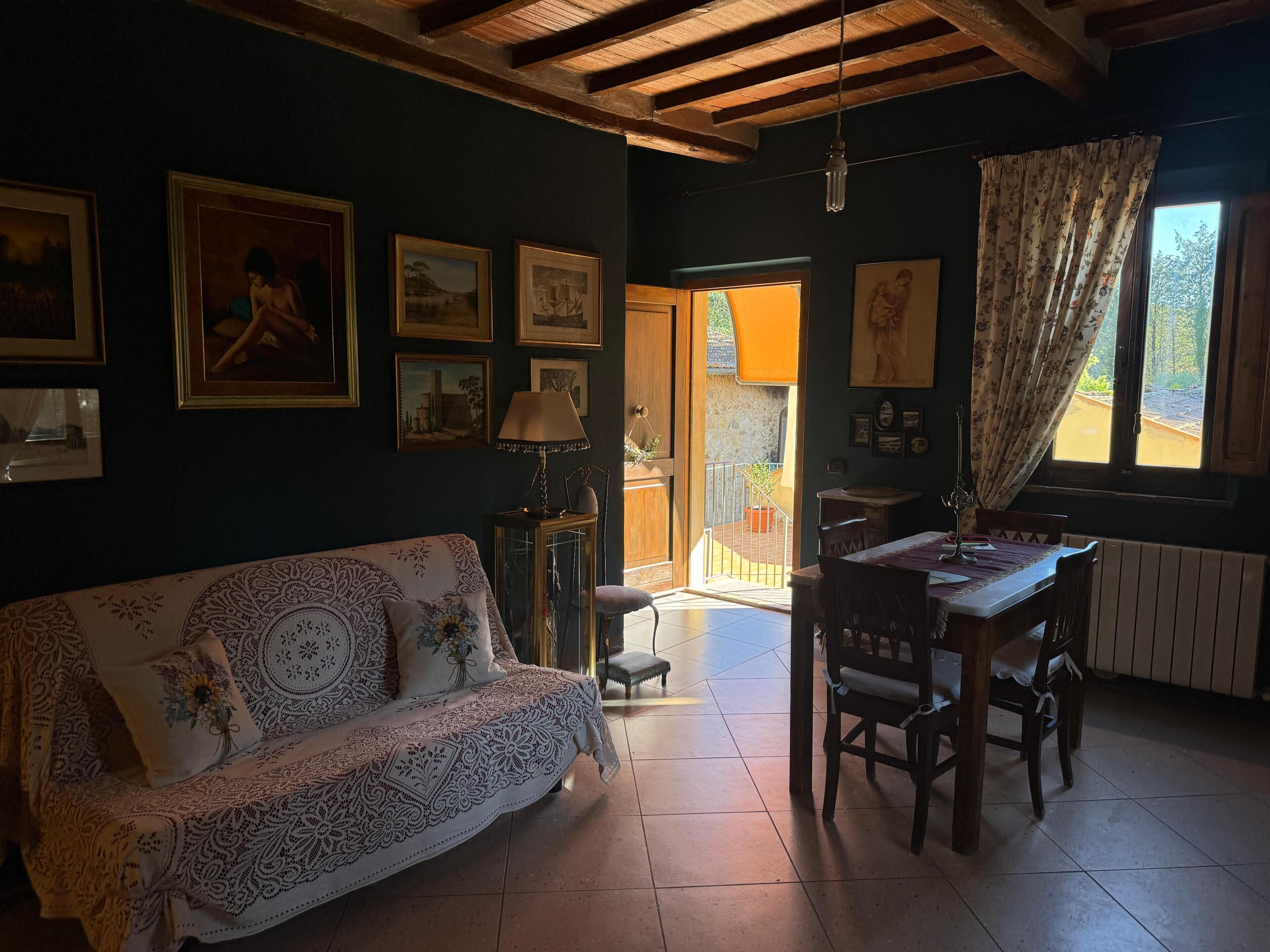 Ein gemütliches Zimmer mit einer Couch, einem Esstisch, Stühlen und Kunstwerken an den Wänden.