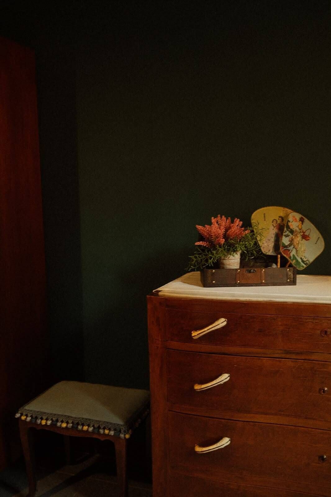 A wooden dresser with drawers and a small stool beside it.