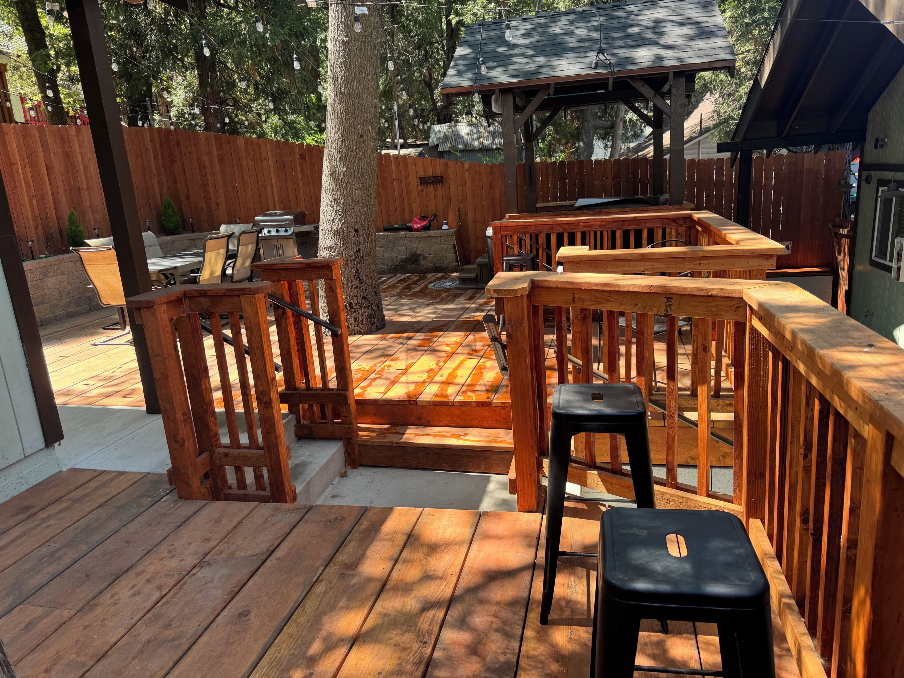 Eine Holzterrasse mit Gartenmöbeln, einem Pergola und einem eingezäunten Hinterhof.