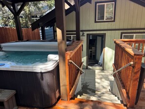 Een jacuzzi, een houten terras en een trap naar een huis.