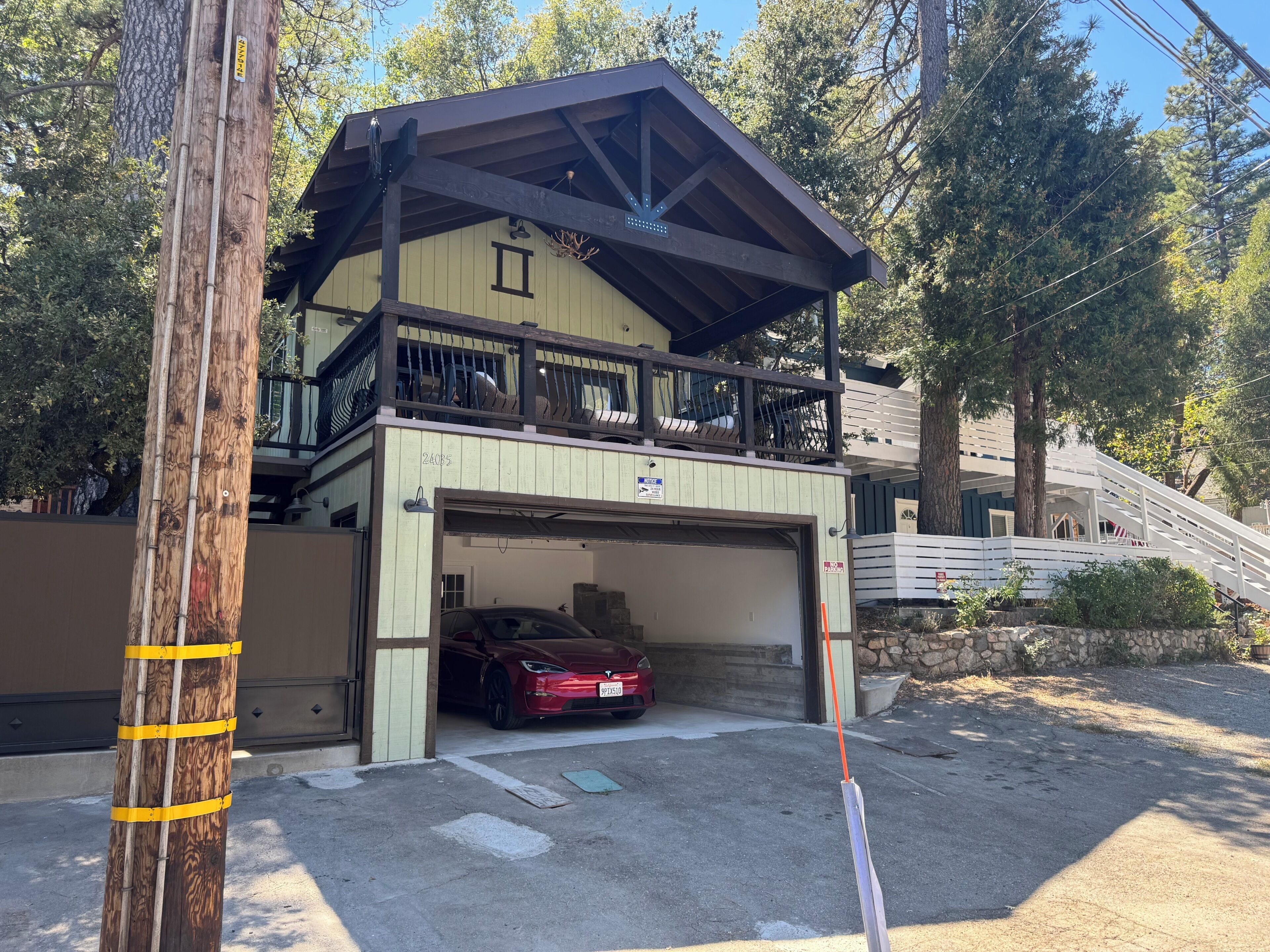 Un bâtiment à deux étages doté d’un garage, d’un balcon et d’un poteau en bois servant de support pour les lignes électriques.