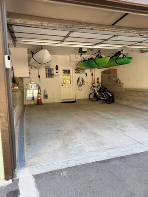 Een garage met een motor, een kajak en een fiets.