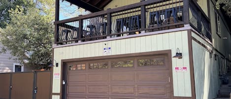 A two-story building with a garage door, a balcony with metal railings, and a 'No Parking' sign.