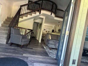 Ein modernes Interieur mit einer geschwungenen Treppe, einer Sitzecke mit Sofas und einer Küche im Hintergrund.