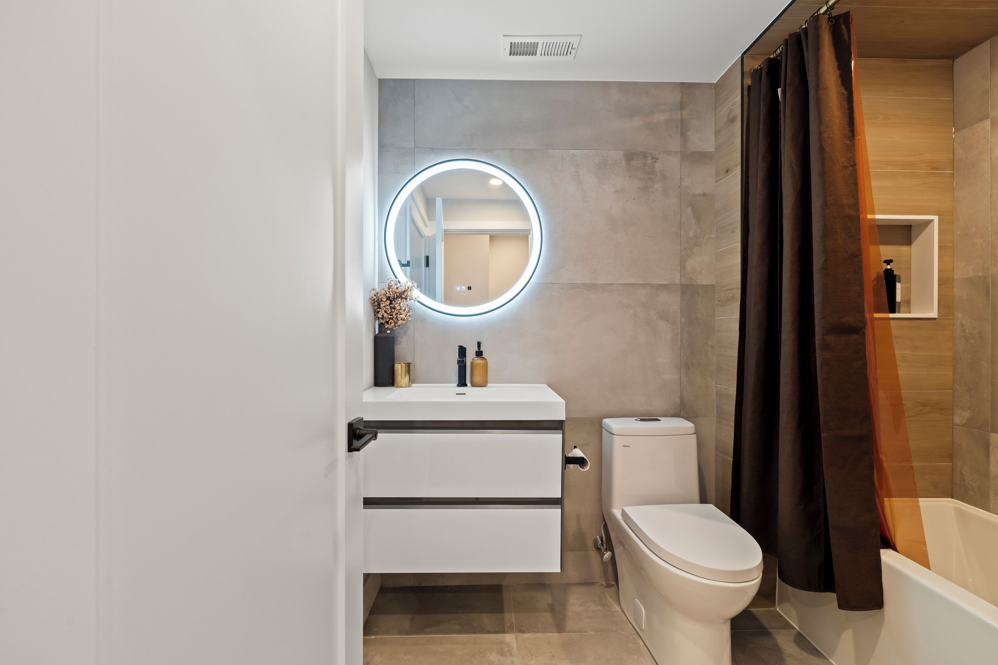 A modern bathroom with a toilet, sink, and bathtub.
