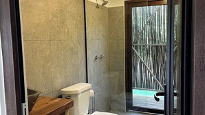 A bathroom with a toilet, shower, and a wooden vanity. - Luxury cabin / Playa Venao (playa venao)