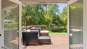 An open sliding door leading to a deck with wicker furniture and a wooden deck. - The Silver Shell SSI - Dog Friendly (St. Simons Island)
