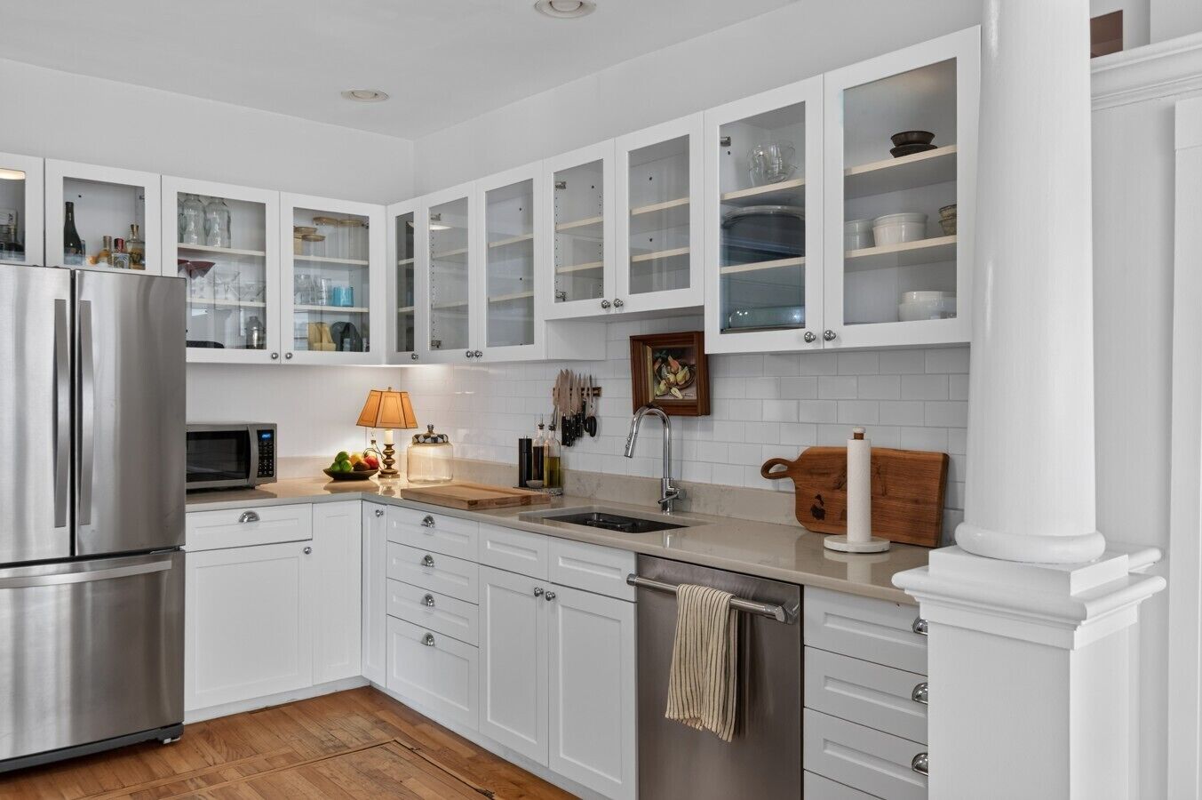 Een moderne keuken met witte kasten, roestvrijstalen apparatuur en een houten aanrecht.