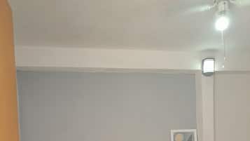 Ein Schlafzimmer mit einem Bett, einem Kopfteil, einem Nachttisch mit Lampe und einem gerahmten Bild an der Wand.