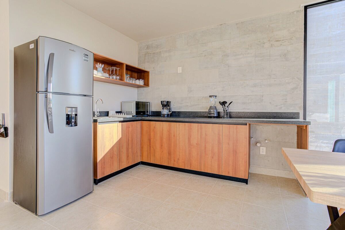 A modern kitchen with a built-in refrigerator, wooden cabinetry, a countertop, and a dining area.