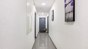 A hallway with white walls, a grey carpet, and a door at the end.