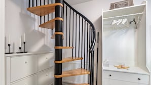 A spiral staircase with black and wooden steps, white storage units, and a white radiator.
