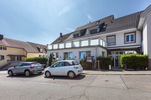 Eine Wohnstraße mit zwei parkenden Autos, einem Haus mit Ziegeldach und der Hausnummer 20.