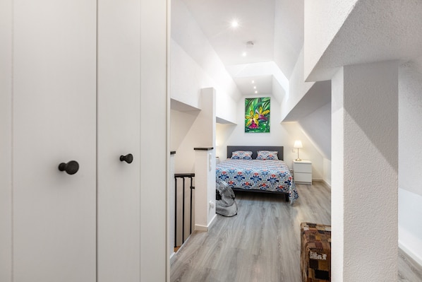 A bedroom with a bed, a nightstand, a lamp, and a painting on the wall.