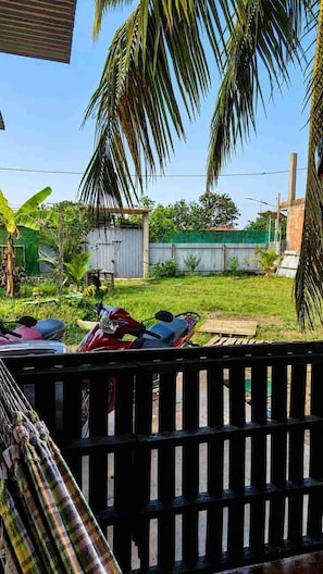 A fenced outdoor area with a grassy lawn, a red scooter, and a green building in the background.