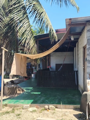 A backyard with a hammock, a pool, and a palm tree.