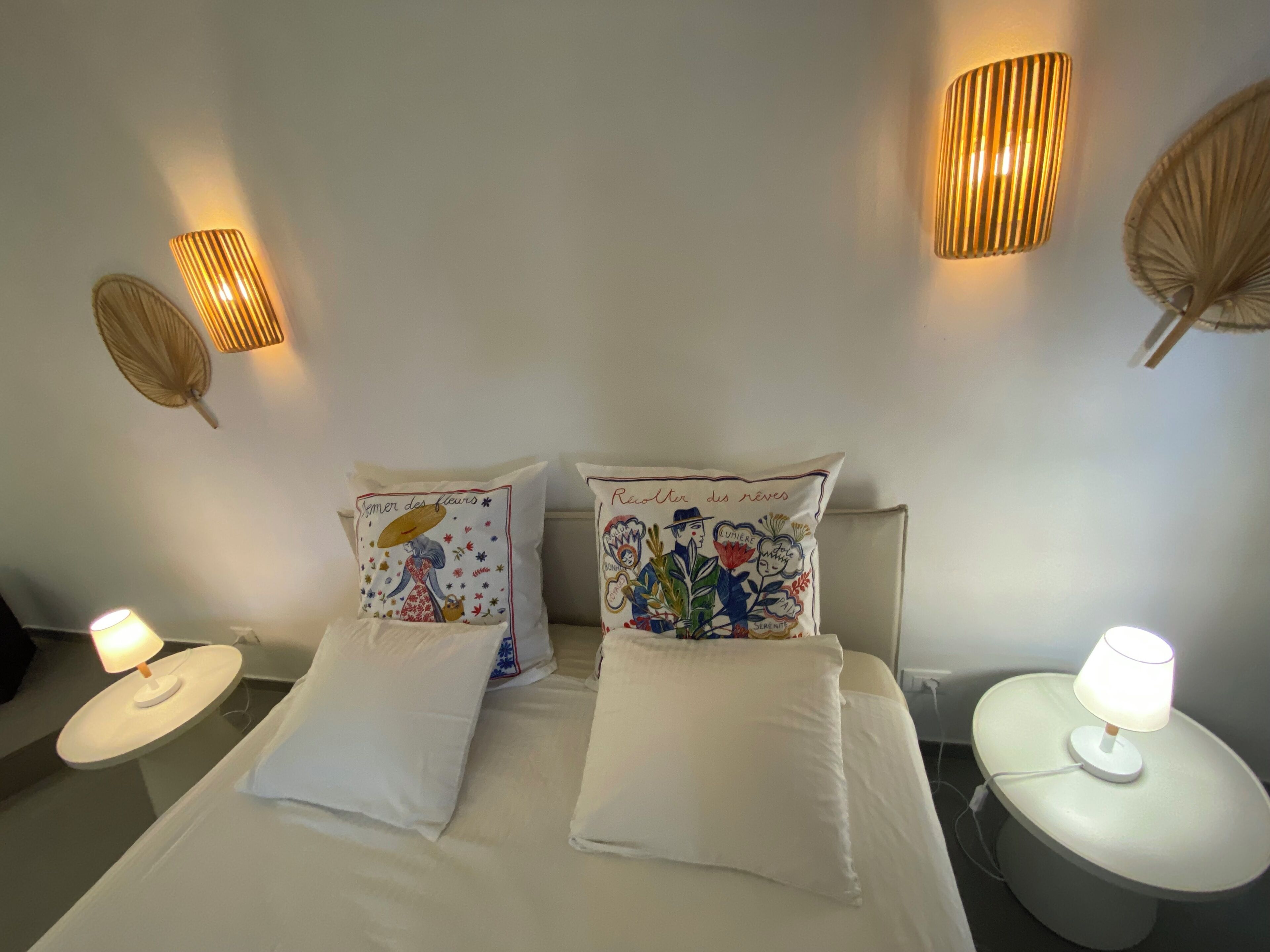 A bed with two pillows, two bedside lamps, and two wall-mounted lamps.