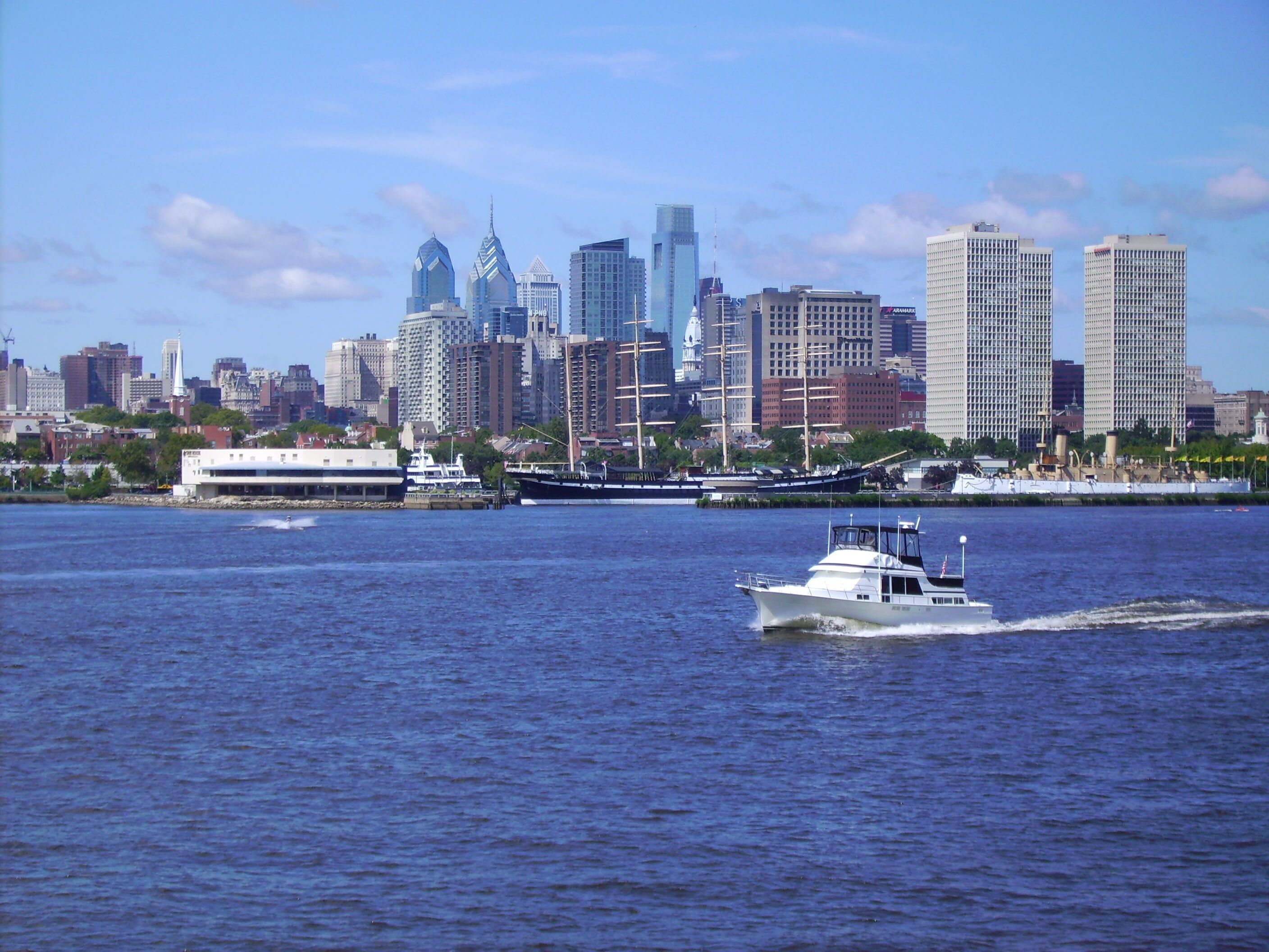 A city skyline with high-rise buildings and a body of water with a boat.