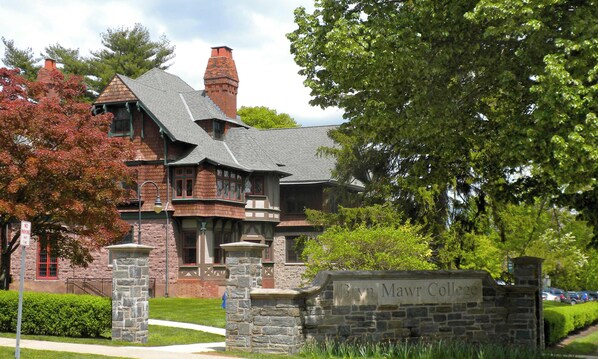 A historic building with a stone facade, a prominent chimney, and a sign indicating it is part of Brown Mawr College.