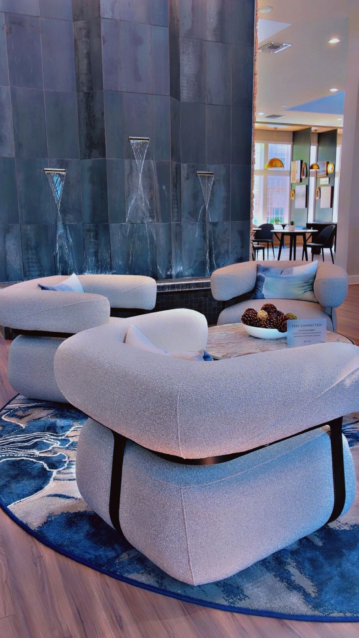 Ein moderner Lounge-Bereich mit einer großen Wanddekoration, Sitzgelegenheiten und einem Tisch mit Kiefernzapfen.