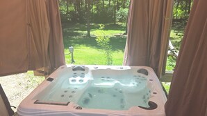 A hot tub under a tent with a view of a green landscape. - Cozy 1-bedroom cabin in serene Magnolia with AC (Magnolia)