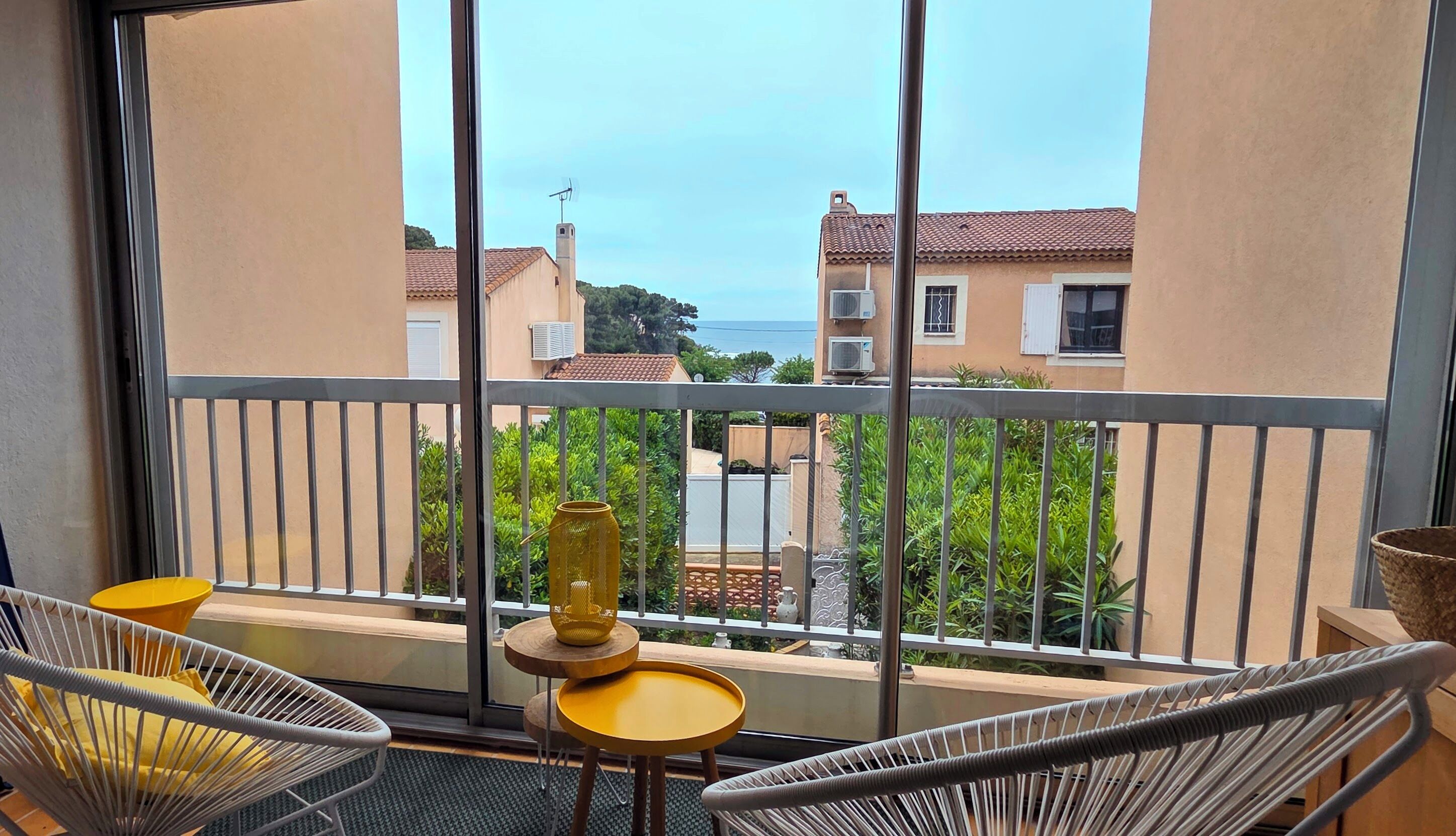 Ein Balkon mit zwei Korbstühlen, einem kleinen runden Tisch und einer dekorativen Vase.