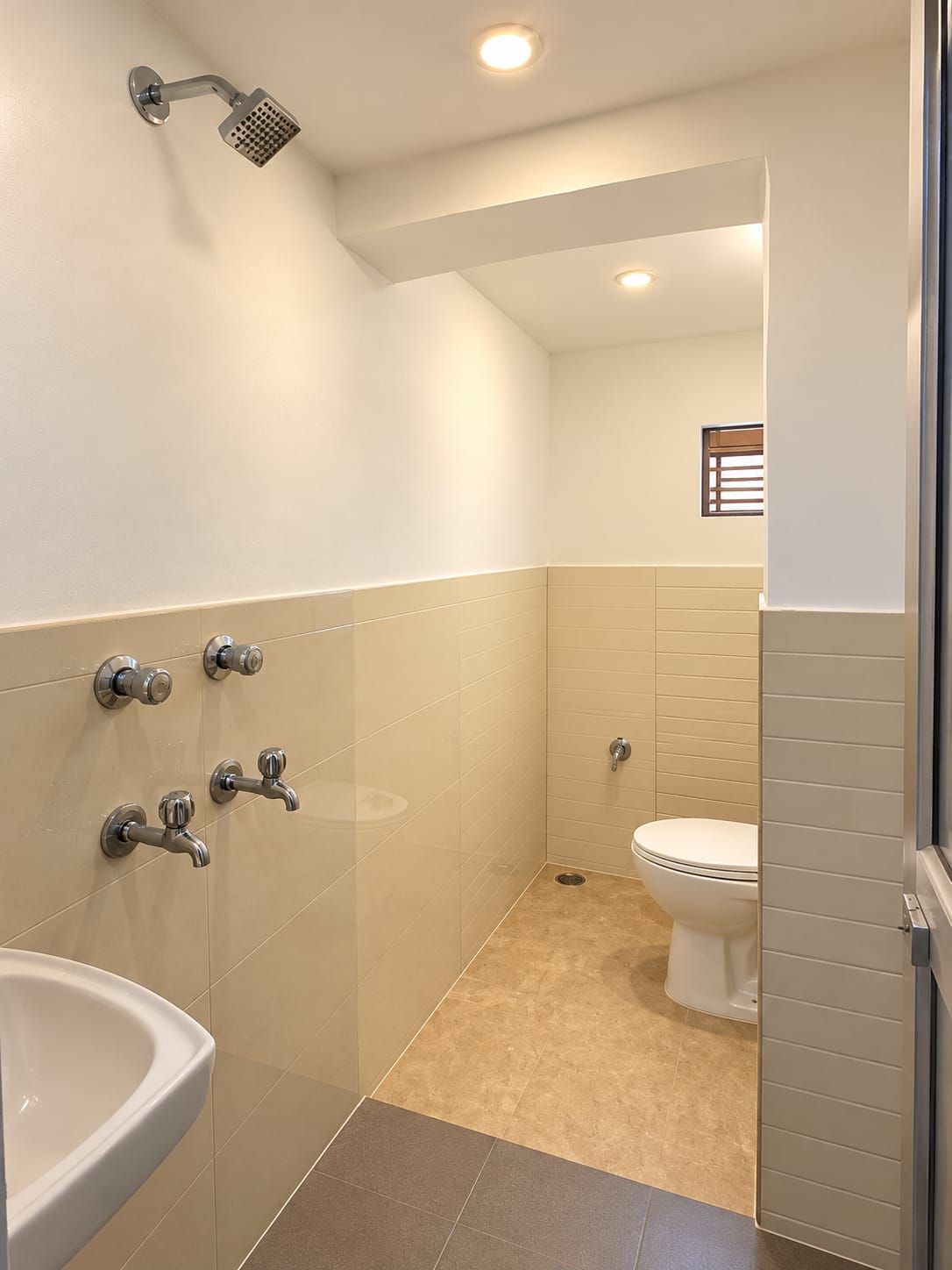 A bathroom with a shower, sink, toilet, and a window.
