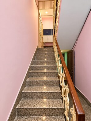 Una escala amb barana de fusta i un aplíc de paret.