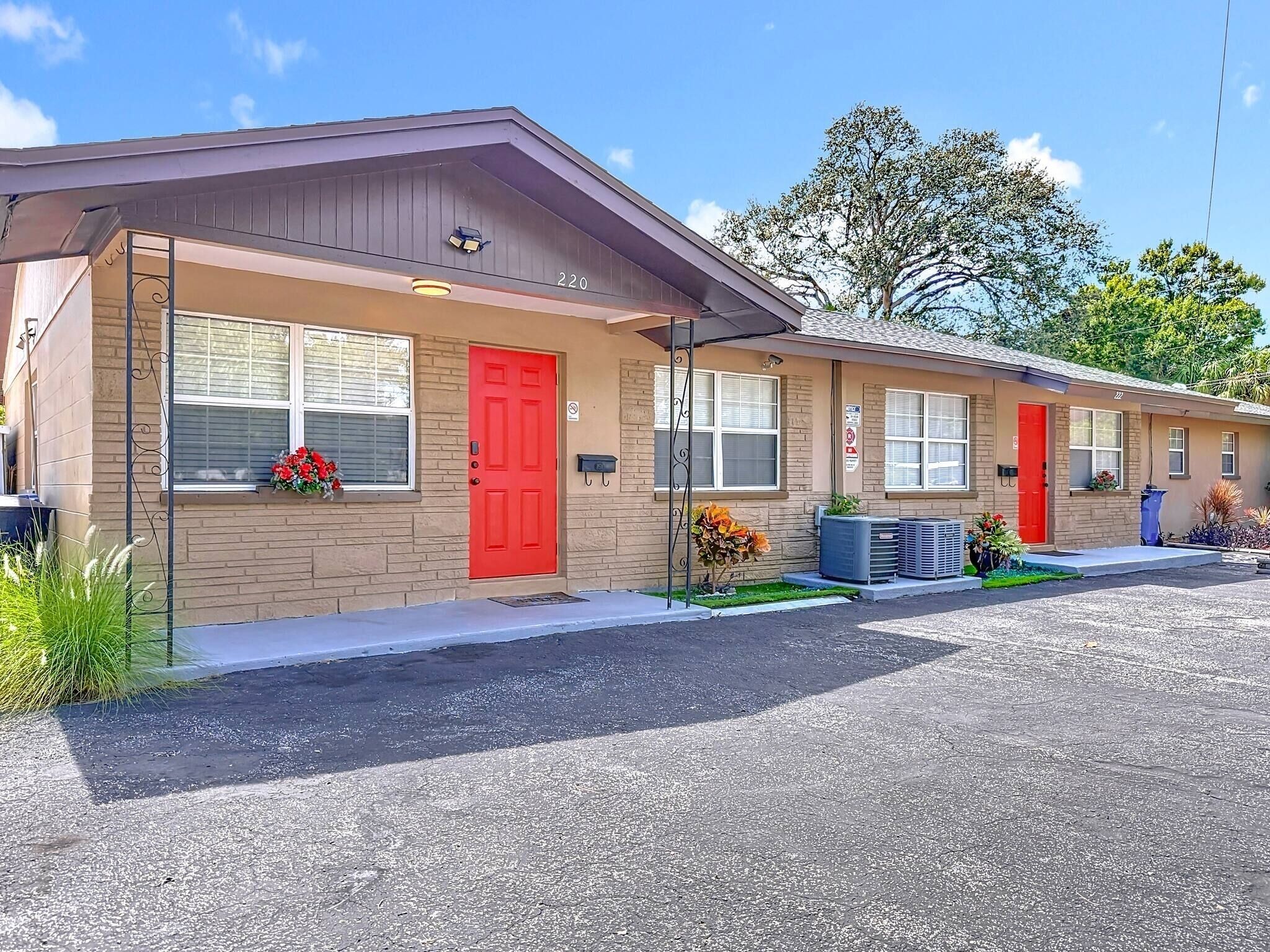 Motel con puerta roja, número 220, y un pequeño jardín con flores.