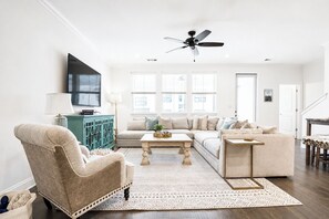 Una sala de estar con sofá, sillón, mesa de centro y televisor.