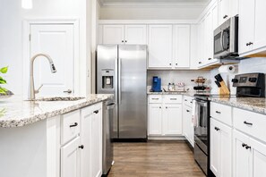 A modern kitchen with white cabinets, stainless steel appliances, a granite countertop, and a wooden floor. - The Getaway, 2mi to SQ, +pool, Velvet Ditch Villas (Oxford)