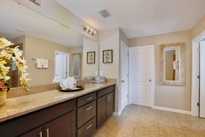 A bathroom with a large mirror, a vanity with a sink, and a towel rack. - The Magic Haven - 5BR - Sleeps 13 - Near Disney (Davenport)