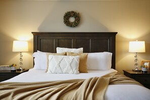 A neatly made bed with white and beige bedding, two bedside lamps, a dark wood headboard, and a wall-mounted wreath. - The Magic Haven - 5BR - Sleeps 13 - Near Disney (Davenport)