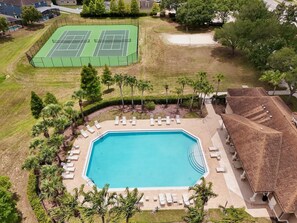 An aerial view of a resort with a swimming pool, sun loungers, and tennis courts. - The Magic Haven - 5BR - Sleeps 13 - Near Disney (Davenport)