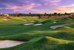 A golf course with bunkers, a water hazard, and a clubhouse in the background. - The Magic Haven - 5BR - Sleeps 13 - Near Disney (Davenport)