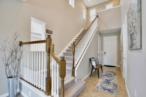 A staircase with wooden railings, a rug on the floor, and a door in the background. - The Magic Haven - 5BR - Sleeps 13 - Near Disney (Davenport)