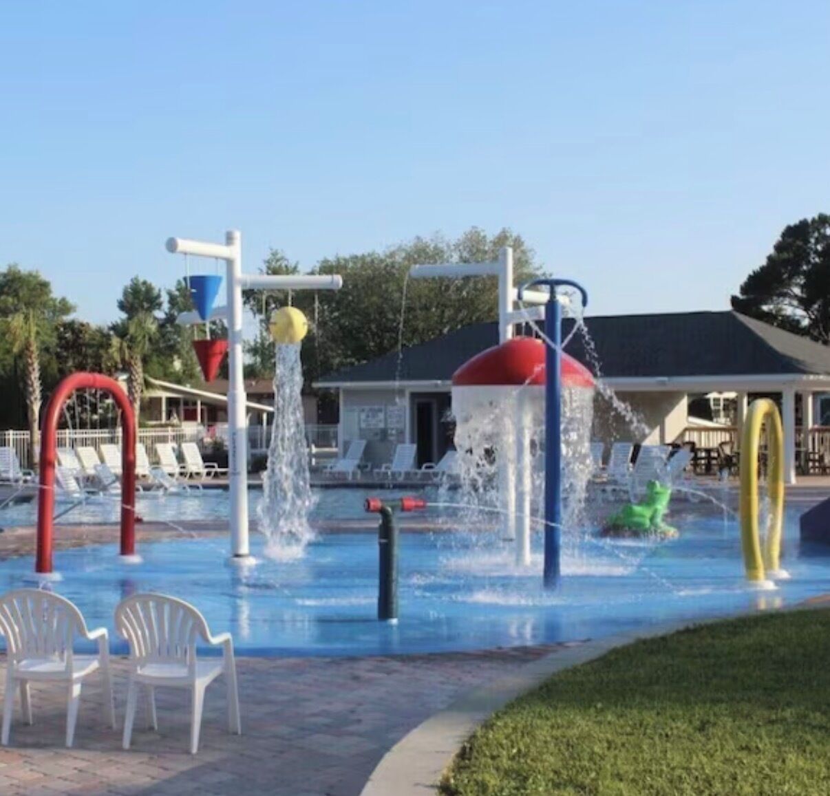 A water park with slides and a pool, surrounded by lounge chairs and a building.