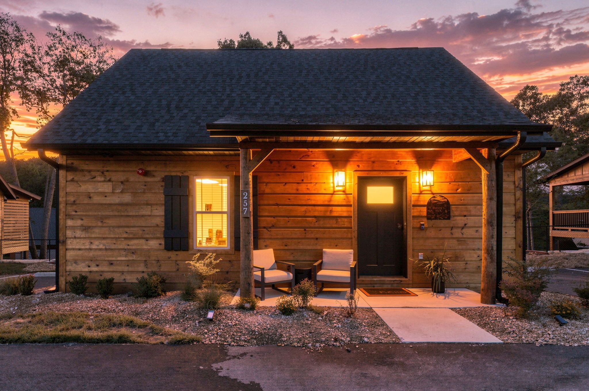 Une cabane en bois avec une véranda, deux chaises et une table.