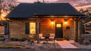 Une cabane en bois avec une véranda, deux chaises et une table.