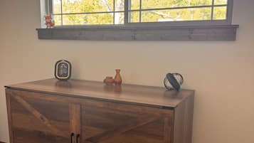 A wooden cabinet with a window above it, a small figurine, and a vase on the window sill.