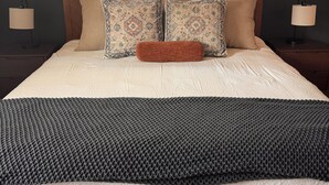 A bed with a wooden headboard, patterned pillows, a knitted throw, and a window with a view of trees. - NewCabin, Pools, Lazy River, Private HotTub, Firepit, near Branson, BigCedar (Hollister)