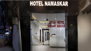 La entrada del Hotel Namaskar, con fachada de vidrio, una escalera que conduce al interior y un letrero de seguridad.