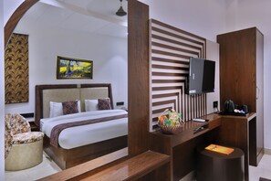 Una habitación de hotel con cama, escritorio, televisor y una silla.