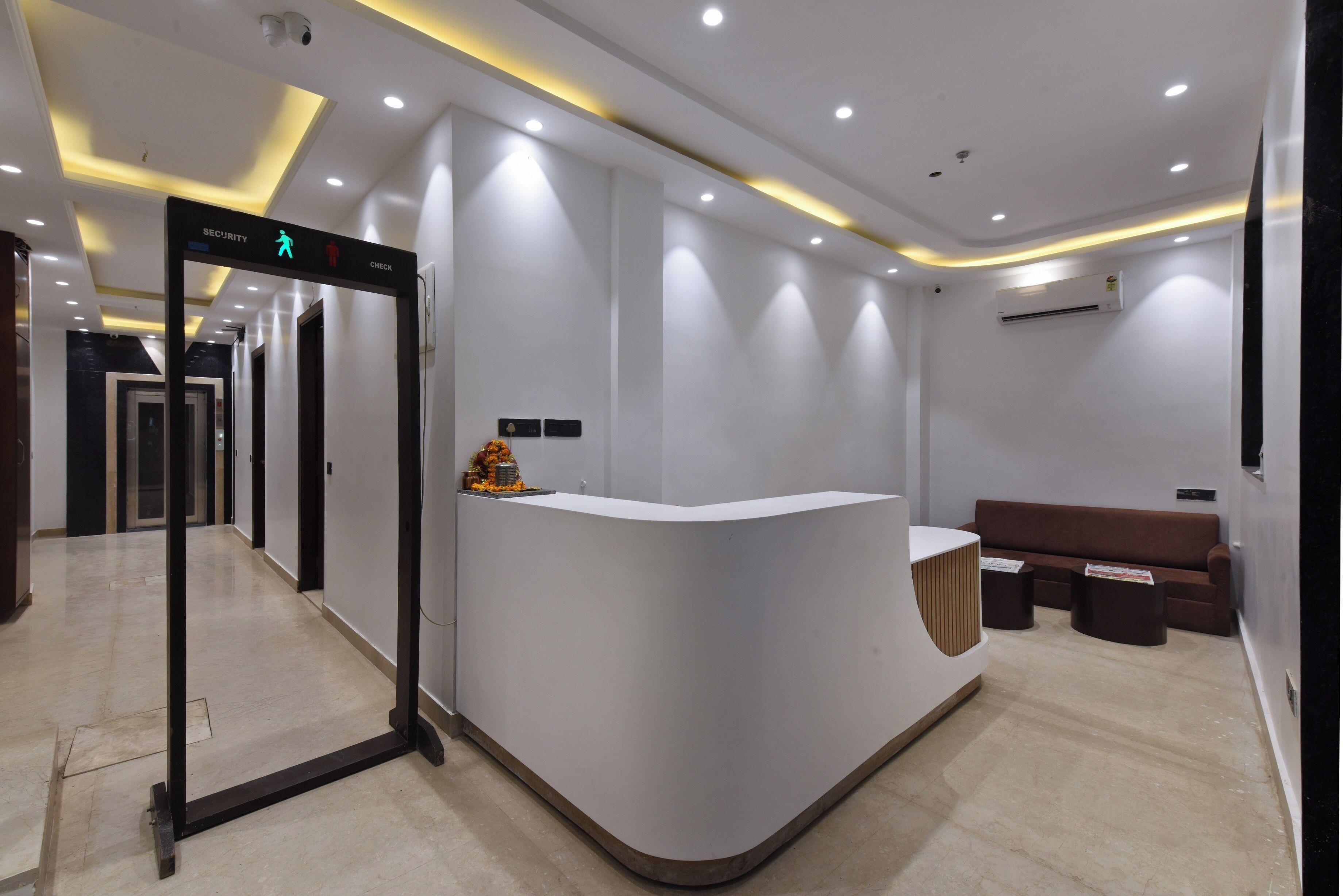 A reception area with a curved reception desk, a security checkpoint, and a seating area with a brown sofa.