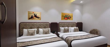 Une chambre d’hôtel avec deux lits, un luminaire au plafond et deux tableaux accrochés au mur.