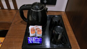 Una cafetera, una bolsita de té y una taza sobre una bandeja.