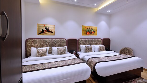 Habitación de hotel con dos camas, cada una con cabeceros estampados y ropa de cama blanca. Dos cuadros cuelgan en la pared sobre las camas.