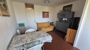Ein gemütlicher Wohnbereich mit Esstisch, einer Couch, einem Schrank und einem Fernseher.