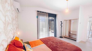 A bedroom with a bed, a wardrobe, a hanging coat rack, and a sliding glass door to a balcony. - Villa for 10 guests, private pool and AC (Saint-Paul)