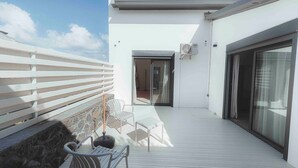 A rooftop terrace with a white railing, a chair, a small table, and a sliding glass door leading to an interior space. - Villa for 10 guests, private pool and AC (Saint-Paul)